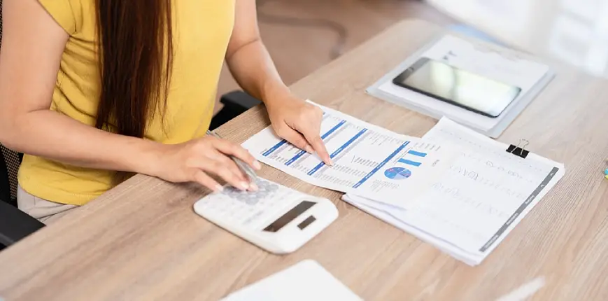 ผู้หญิงกำลังคำนวณหนี้สินต่อรายได้ให้ถูกต้องเพื่อวางแผนการเงินปีหน้า