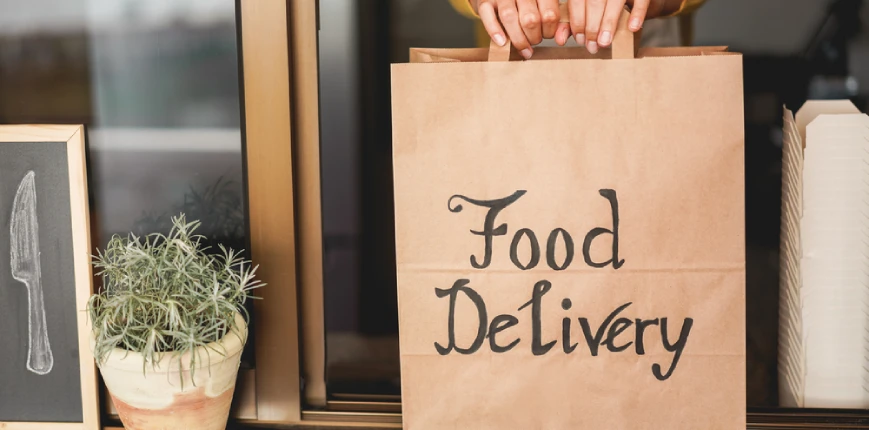 ผู้หญิงเปิดร้านอาหารออนไลน์ กำลังส่งถุงสินค้าให้ไรเดอร์